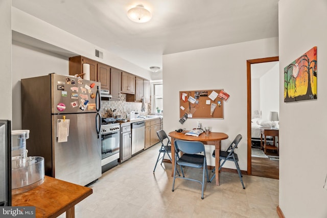 kitchen featuring appliances with stainless steel finishes, exhaust hood, and tasteful backsplash