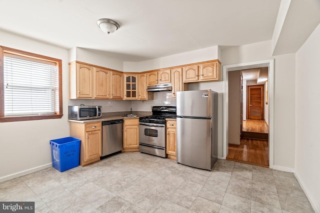 kitchen featuring light brown cabinetry, stainless steel appliances, backsplash, and light tile patterned floors