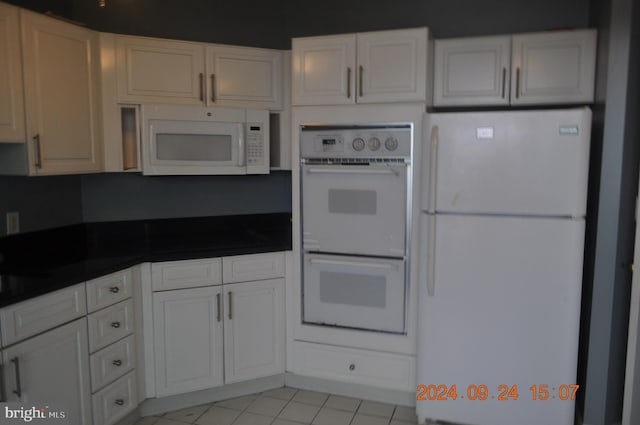 kitchen featuring white appliances, light tile patterned floors, and white cabinets