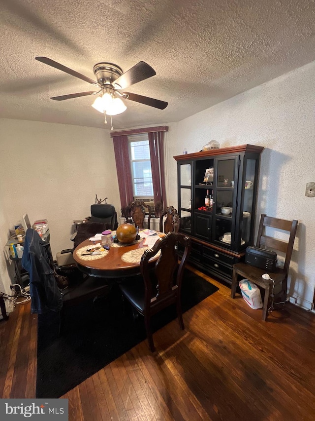 dining room with dark wood-type flooring, a textured ceiling, and ceiling fan