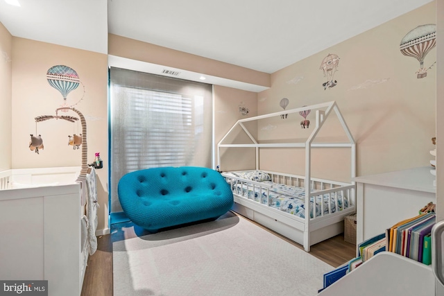 bedroom featuring a nursery area and hardwood / wood-style floors