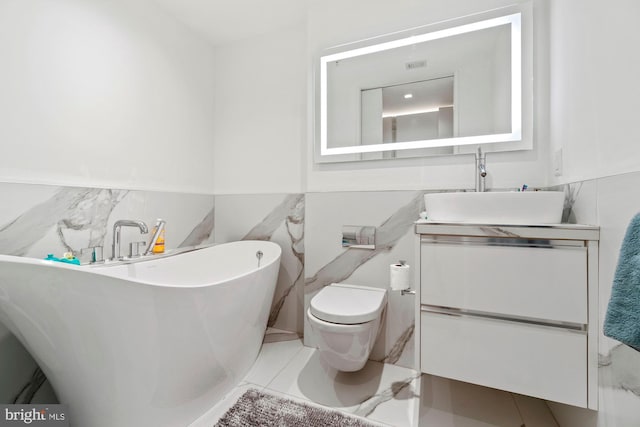 bathroom featuring a tub to relax in, vanity, toilet, and tile walls