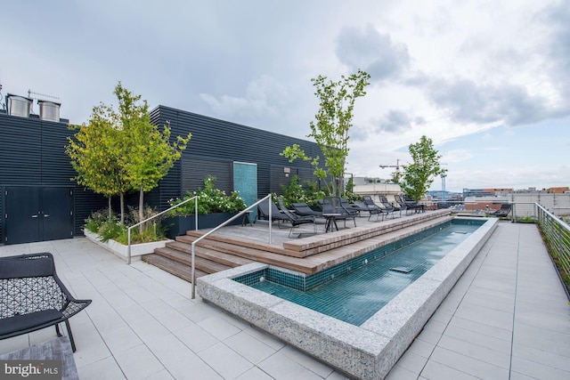 view of swimming pool featuring a jacuzzi and a patio