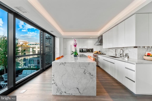 kitchen featuring backsplash, light wood-type flooring, a kitchen island, white cabinets, and high end stainless steel range oven