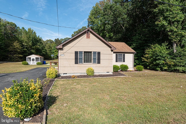 bungalow-style house with a front lawn and a shed