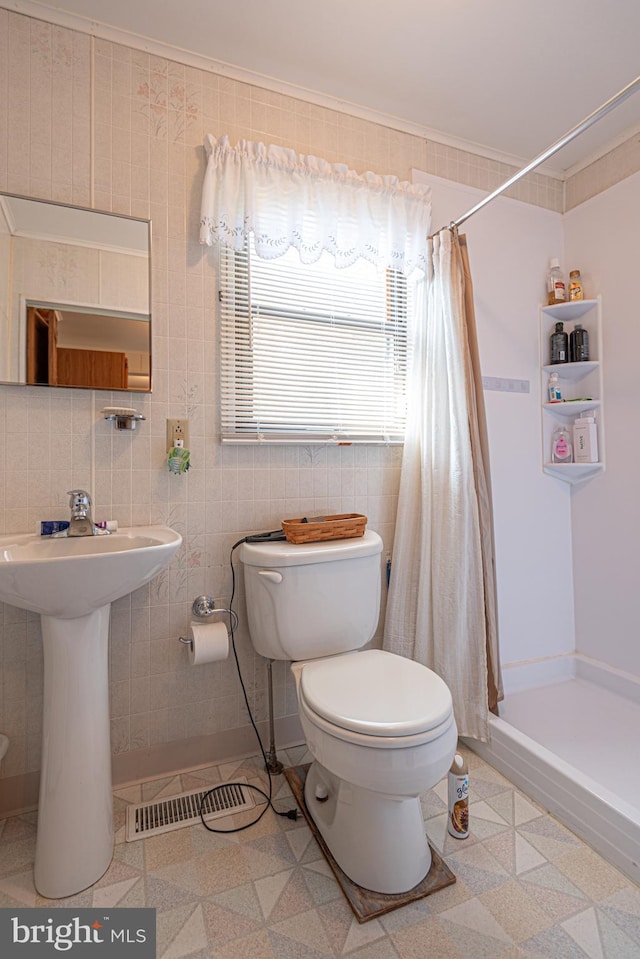 bathroom featuring a shower with shower curtain, sink, ornamental molding, and toilet