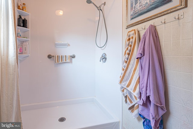 bathroom with a shower with curtain and tile walls