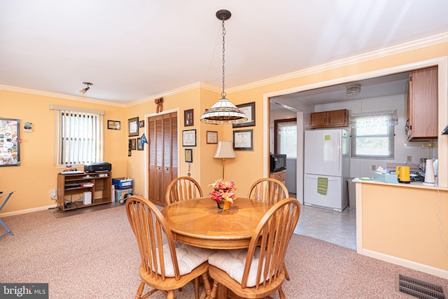 dining space featuring ornamental molding and light carpet