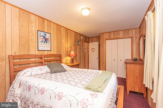 bedroom featuring a textured ceiling, a closet, and wood walls