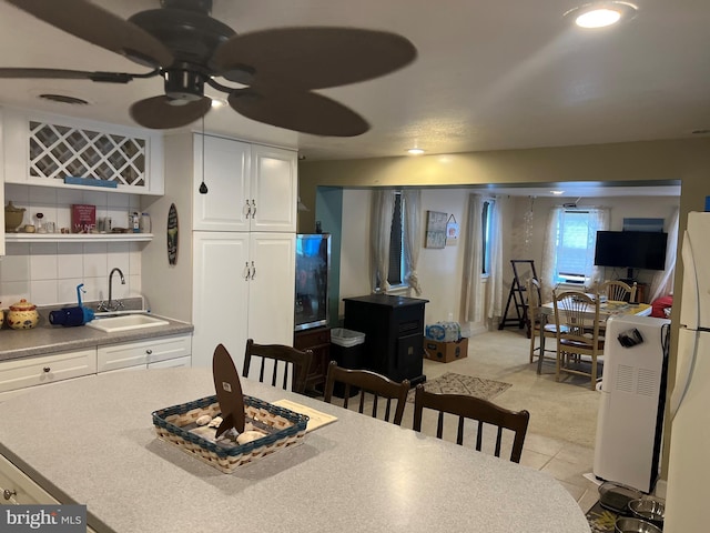 tiled dining area with ceiling fan and sink