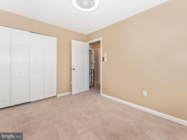 unfurnished bedroom with light colored carpet and a closet