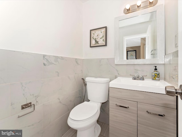 bathroom featuring vanity, toilet, and tile walls