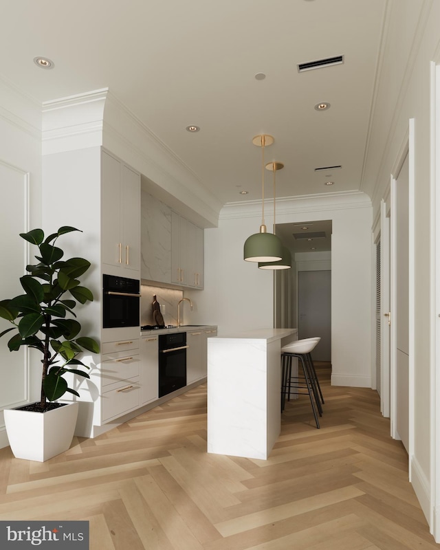 kitchen with crown molding, pendant lighting, light parquet flooring, and oven