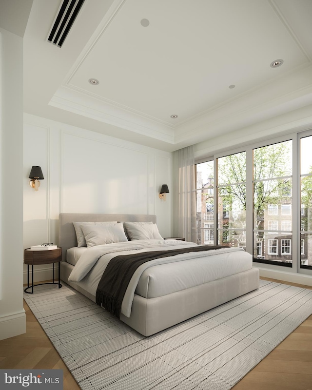 bedroom with light hardwood / wood-style flooring and a tray ceiling