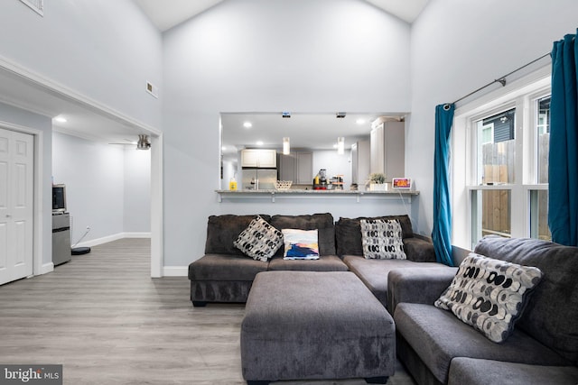 living room with high vaulted ceiling and light wood-type flooring