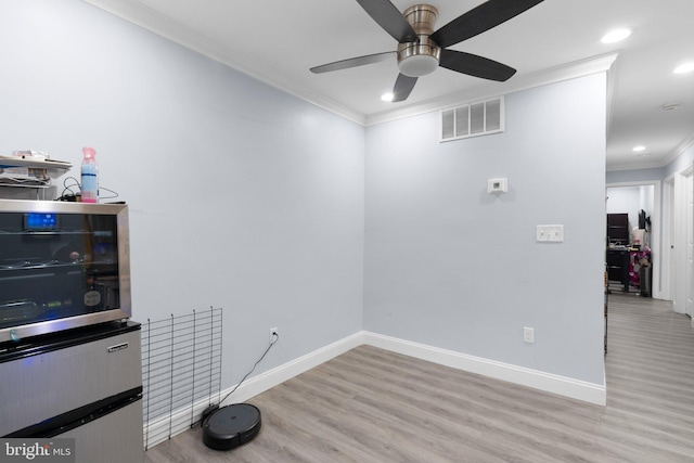 interior space with light wood-type flooring, ornamental molding, and ceiling fan