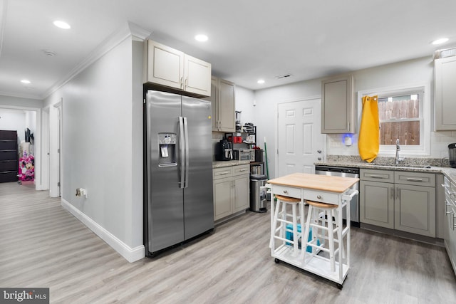 kitchen with sink, light hardwood / wood-style flooring, stainless steel appliances, and tasteful backsplash