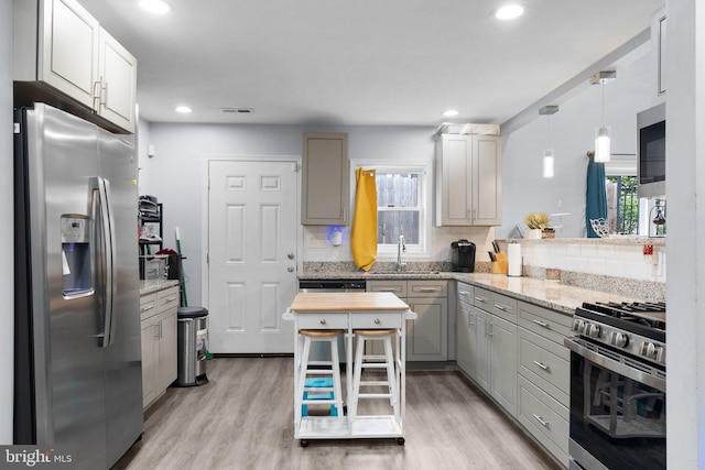 kitchen with decorative light fixtures, light hardwood / wood-style flooring, stainless steel appliances, and plenty of natural light