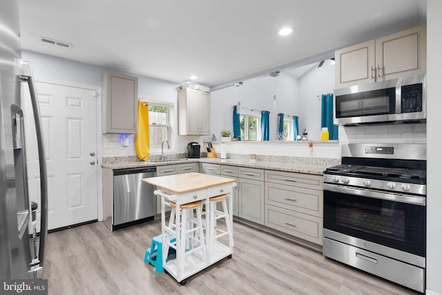 kitchen featuring appliances with stainless steel finishes, light wood-type flooring, sink, and a wealth of natural light