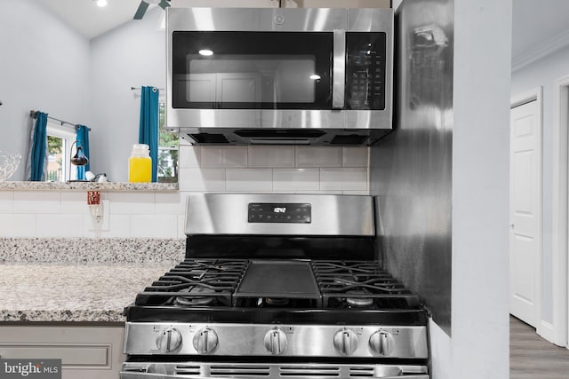 kitchen featuring light stone countertops, appliances with stainless steel finishes, crown molding, and dark hardwood / wood-style flooring