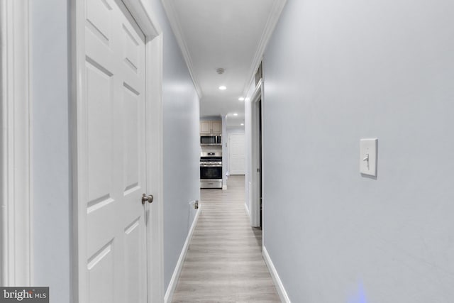 hallway with ornamental molding and light hardwood / wood-style flooring