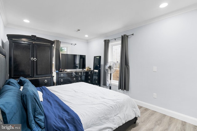 bedroom with multiple windows, ornamental molding, and light hardwood / wood-style flooring