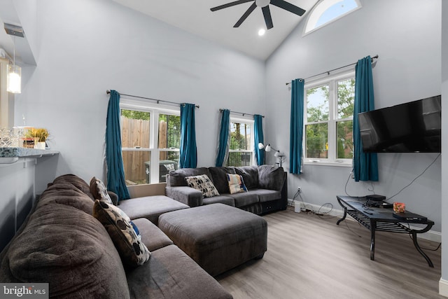 living room featuring light hardwood / wood-style flooring, ceiling fan, and high vaulted ceiling