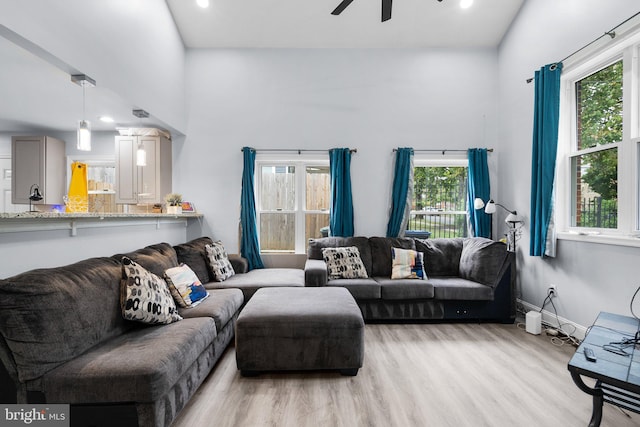 living room featuring light wood-type flooring, ceiling fan, and a wealth of natural light