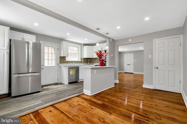 kitchen with light hardwood / wood-style flooring, backsplash, stainless steel appliances, white cabinets, and decorative light fixtures