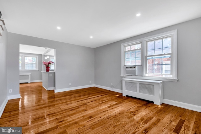 unfurnished living room with radiator, cooling unit, and light hardwood / wood-style flooring