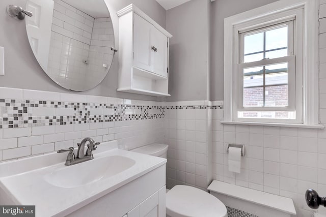 bathroom with vanity, toilet, and tile walls