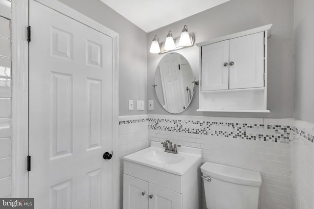 bathroom with vanity, toilet, and tile walls