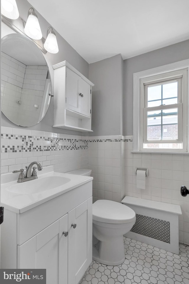 bathroom with vanity, radiator, tile walls, and toilet