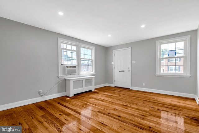 unfurnished room featuring cooling unit, radiator, and light hardwood / wood-style floors