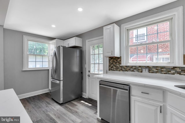 kitchen featuring stainless steel appliances, white cabinetry, backsplash, and light hardwood / wood-style flooring