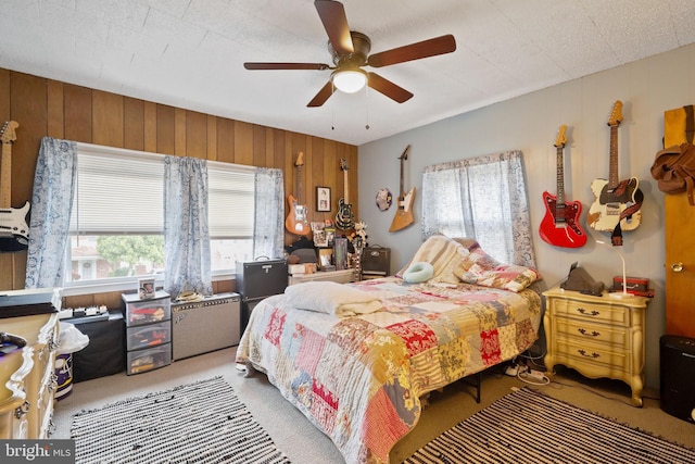 bedroom featuring wood walls, light colored carpet, and ceiling fan