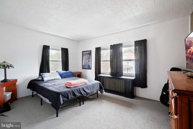 carpeted bedroom with a textured ceiling and wood walls