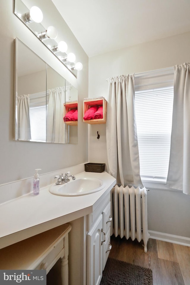 bathroom with hardwood / wood-style floors, vanity, and radiator heating unit