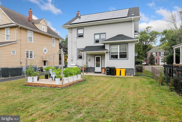 rear view of house featuring solar panels, a yard, and a patio