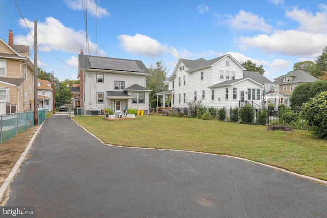 view of front facade featuring solar panels and a front lawn