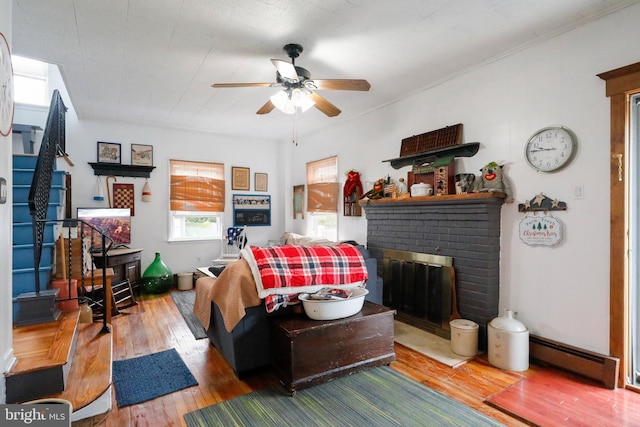 living room with a fireplace, ceiling fan, wood-type flooring, and baseboard heating