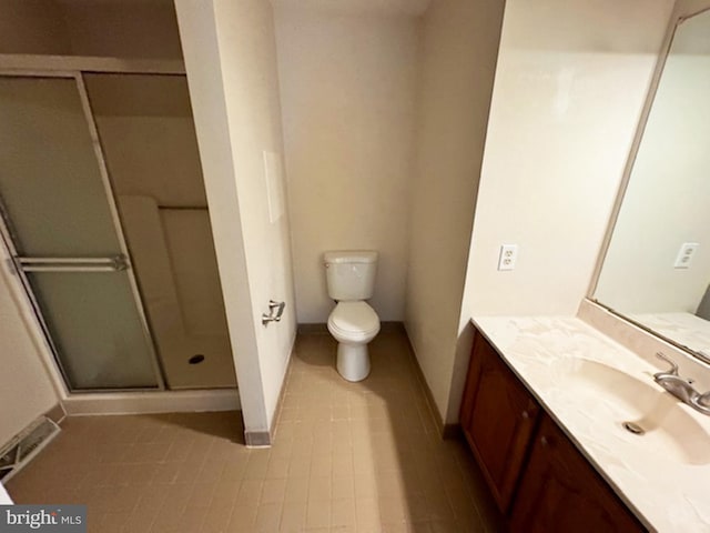 bathroom featuring vanity, a shower with shower door, toilet, and tile patterned floors