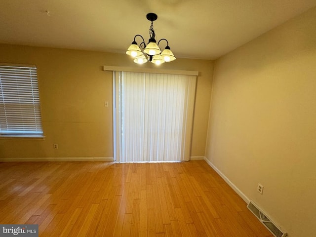 empty room featuring an inviting chandelier and light wood-type flooring