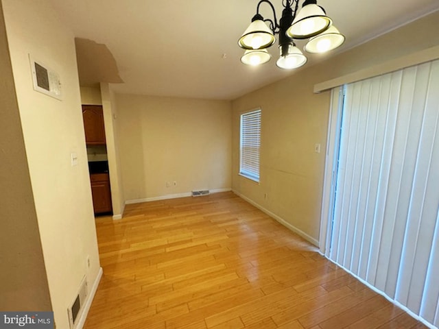 empty room with an inviting chandelier and light wood-type flooring