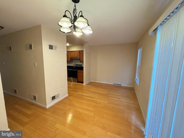 empty room with light wood-type flooring and a chandelier