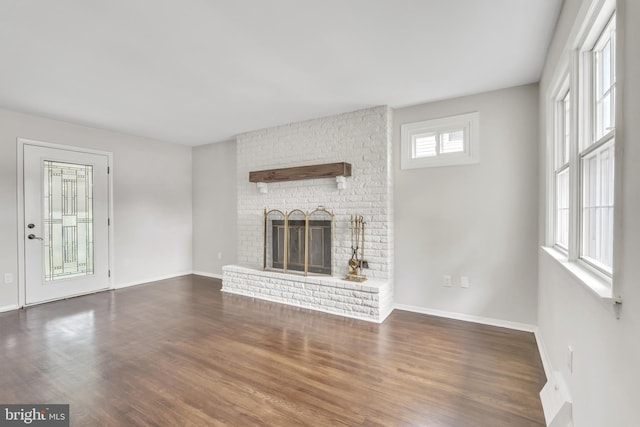 unfurnished living room featuring a fireplace and dark wood-type flooring