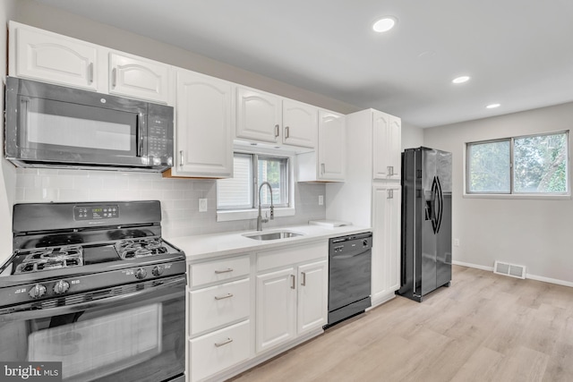 kitchen featuring black appliances, white cabinets, and sink