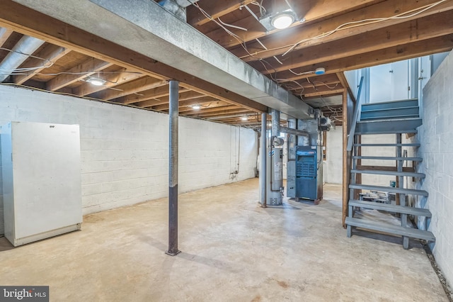 basement with white fridge, heating unit, and water heater