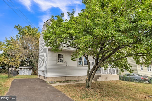 view of side of property with a yard and a storage shed