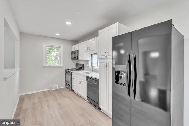 kitchen featuring sink, white cabinets, black appliances, and light hardwood / wood-style floors